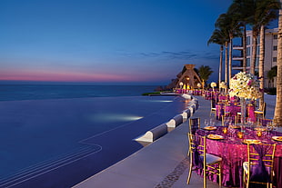 photo of round pink tables and chairs beside body of water