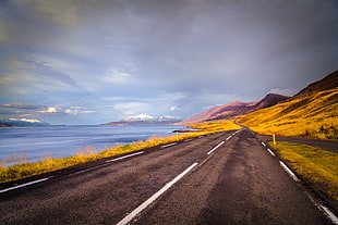 photo of a road near mountains and river HD wallpaper