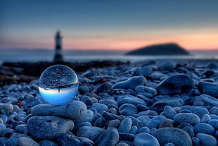 ball on gray stones near lighthouse at golden hour