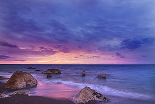 photo of rocks on seashore near ocean during golden hour