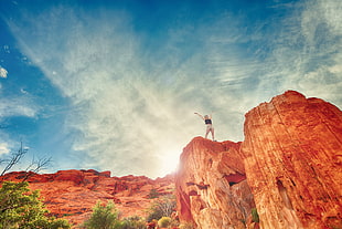 person on top of brown cliff during daytime HD wallpaper