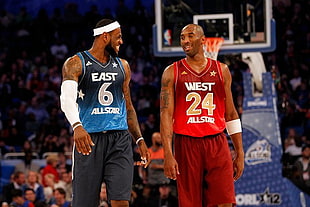 two men in East and West basketball jersey walking on basketball court