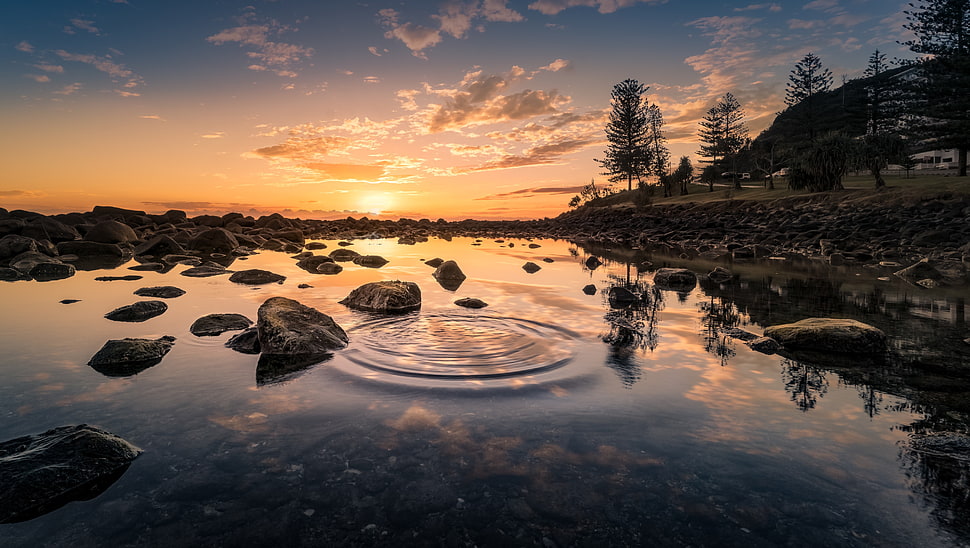 lake surrounded by stones during sunset HD wallpaper