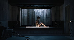 naked woman sitting on platform with lights near window