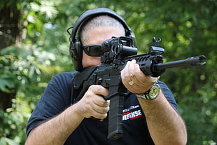 man wears black shirt holding rifle