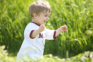 boy wearing white and brown crew neck t-shirt running happy on the green grass HD wallpaper