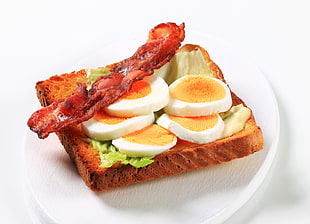 fried bacon and sliced boiled eggs on top of toasted sandwich