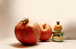 red apple fruit beside glass bottle on white wooden surface
