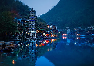 temple next to town and mountain beside body of water during night