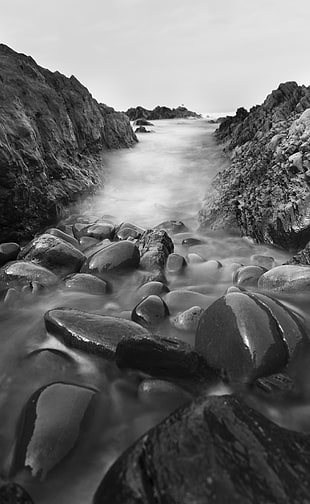 grayscale photography of stone with body of water