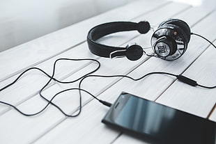 black and grey corded headphones connected to black android smartphone on white wooden surface HD wallpaper