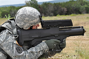 man wearing digital camouflage uniform holding rifle