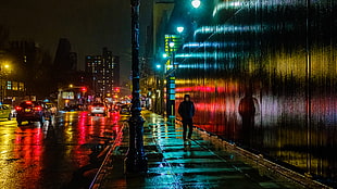 photo of man walking across the alley at night, east side