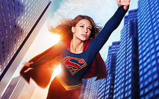 Supergirl flying between highrise building