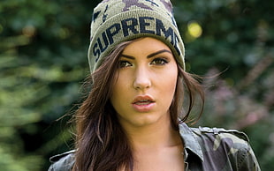photo of woman in green Supreme knit cap and camouflage jacket