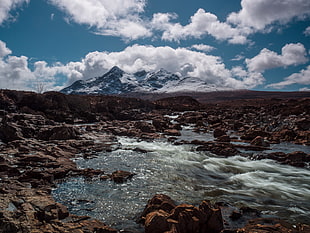 river near mountain under white clouds