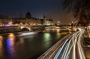 time lapse photography of concrete road near river and bridge with moving cars at night time, paris, seine HD wallpaper