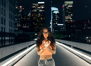 woman in orange crop top in the middle of the street during night time