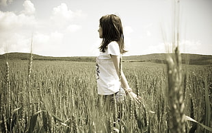 woman in white crew-neck shirt standing on wheat field during daytime