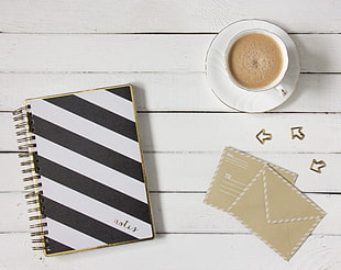 black and white stripe notebook and white ceramic teacup with saucer