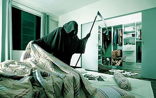 person wearing black cape holds scythe in room