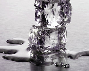two melted ice cubes on gray surface