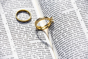 pair of gold-colored rings on page of book