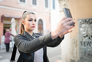 woman wearing black jacket taking selfie during daytime