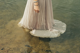 person wearing white dress on body of water