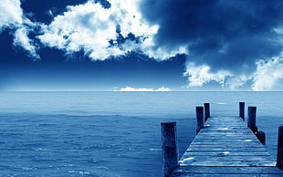 wooden dock under blue cloudy sky