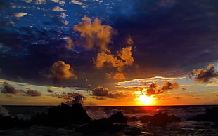 silhouette of rock formations on shore during golden hour
