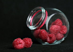 close up photo of red fruits in clear glass jar