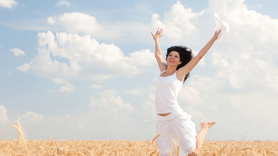 woman wearing white tank top jump on brown grass field during daytime HD wallpaper