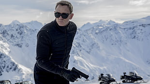 man in black bubble zip-up jacket holding black automatic rifle on snowy mountain during daytime HD wallpaper