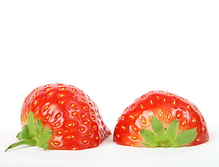 two red sliced strawberries on white surface