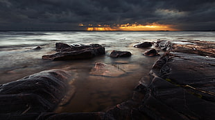 landscape photography of rocks near seashore during golden hour