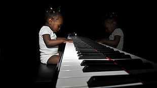 toddler in white short-sleeved shirt sitting and playing piano