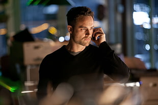 man in black long-sleeved top holding black cellular phone