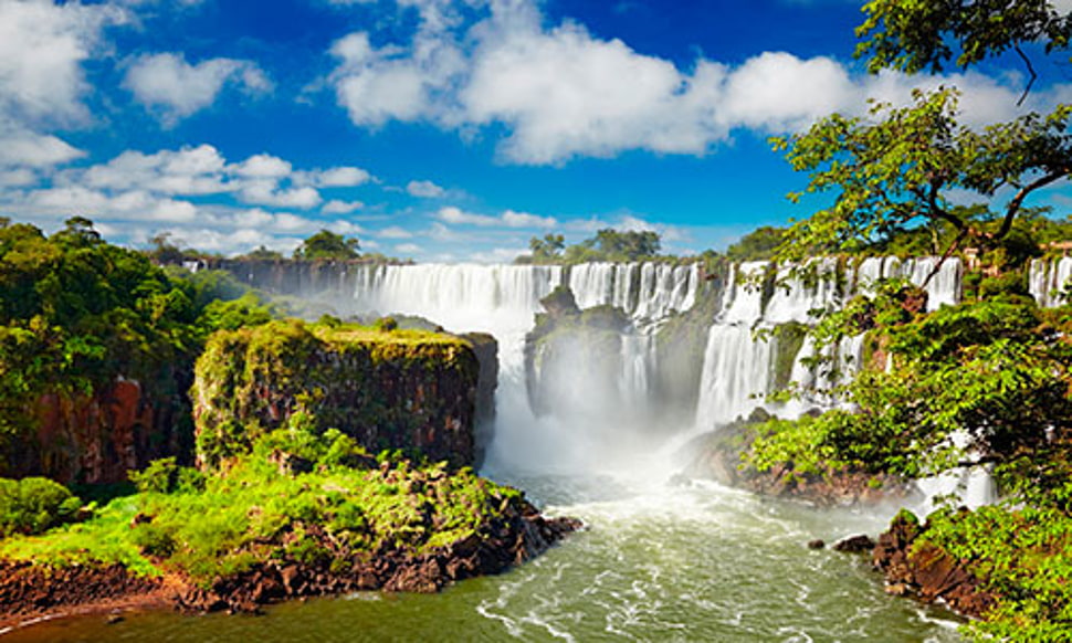 falls beside trees under cloudy blue sky HD wallpaper