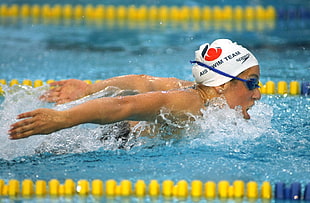 person wearing blue swimming goggles swimming on the pool