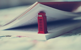 photo of red telephone booth on open textbook HD wallpaper