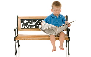 boy holding newspaper while sitting on bench