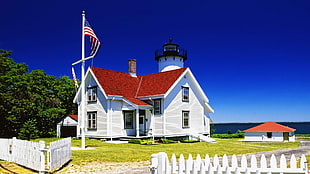 white and brown wooden house beside flag of U.S.A pole near body of water