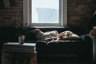 woman sleeping on sofa near window and table