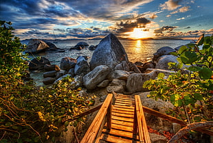 photo of brown wooden dock near beach stone during sunset