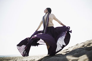woman in white turtle-neck and purple maxi skirt looking up