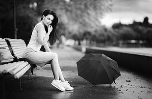 grayscale photography of woman in white tank top and white skirt sitting on white bench