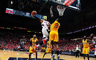 man in white jersey shirt about to dunk the ball while man in yellow jersey guarding and trying to block HD wallpaper