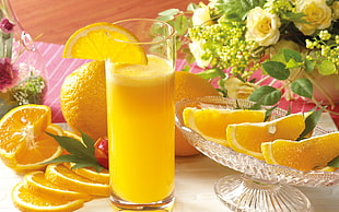 orange juice in clear drinking glass surrounded with slice of orange fruits