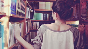 woman in white and gray long sleeve top inside library